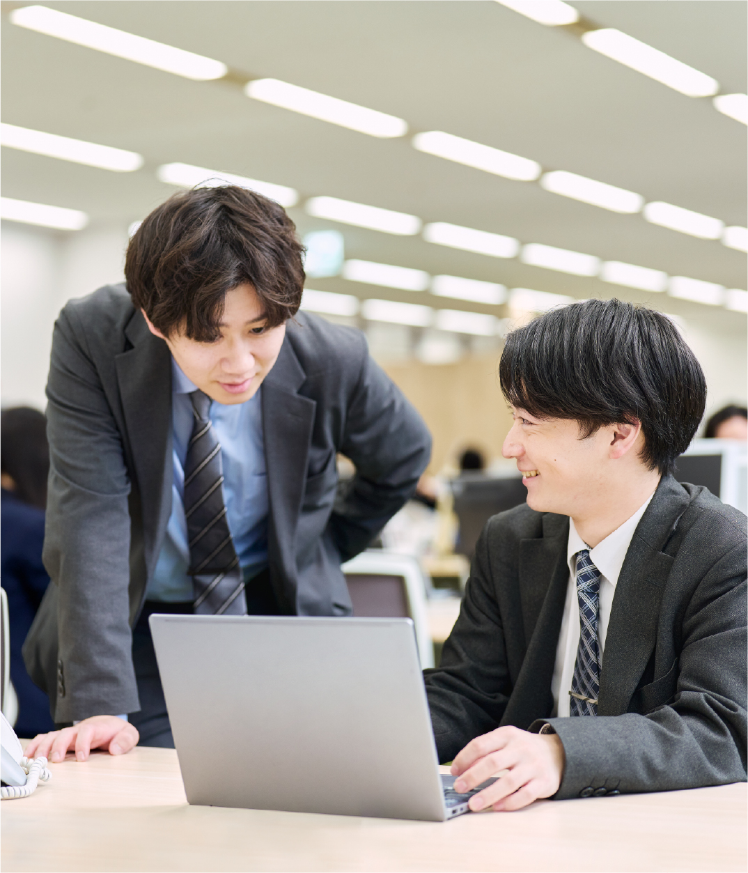 パソコンを見ながら話す2人の社員